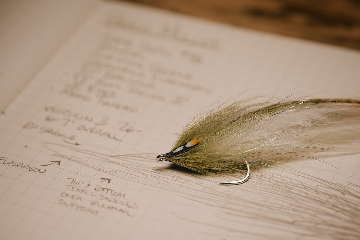 a closeup photo of the Beach Mullet tarpon fly by Two Aught resting on it’s corresponding page in my fly tying journal