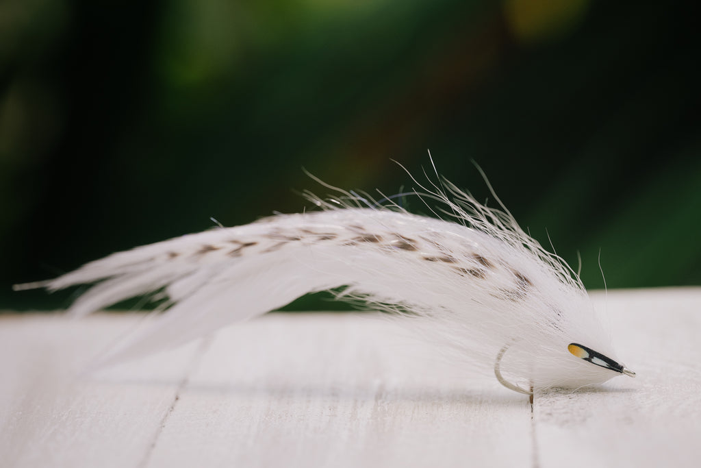 a closeup photo of the Beach Mullet tarpon fly in white colorway tied by Josh Idol at Two Aught Fly Fishing Co