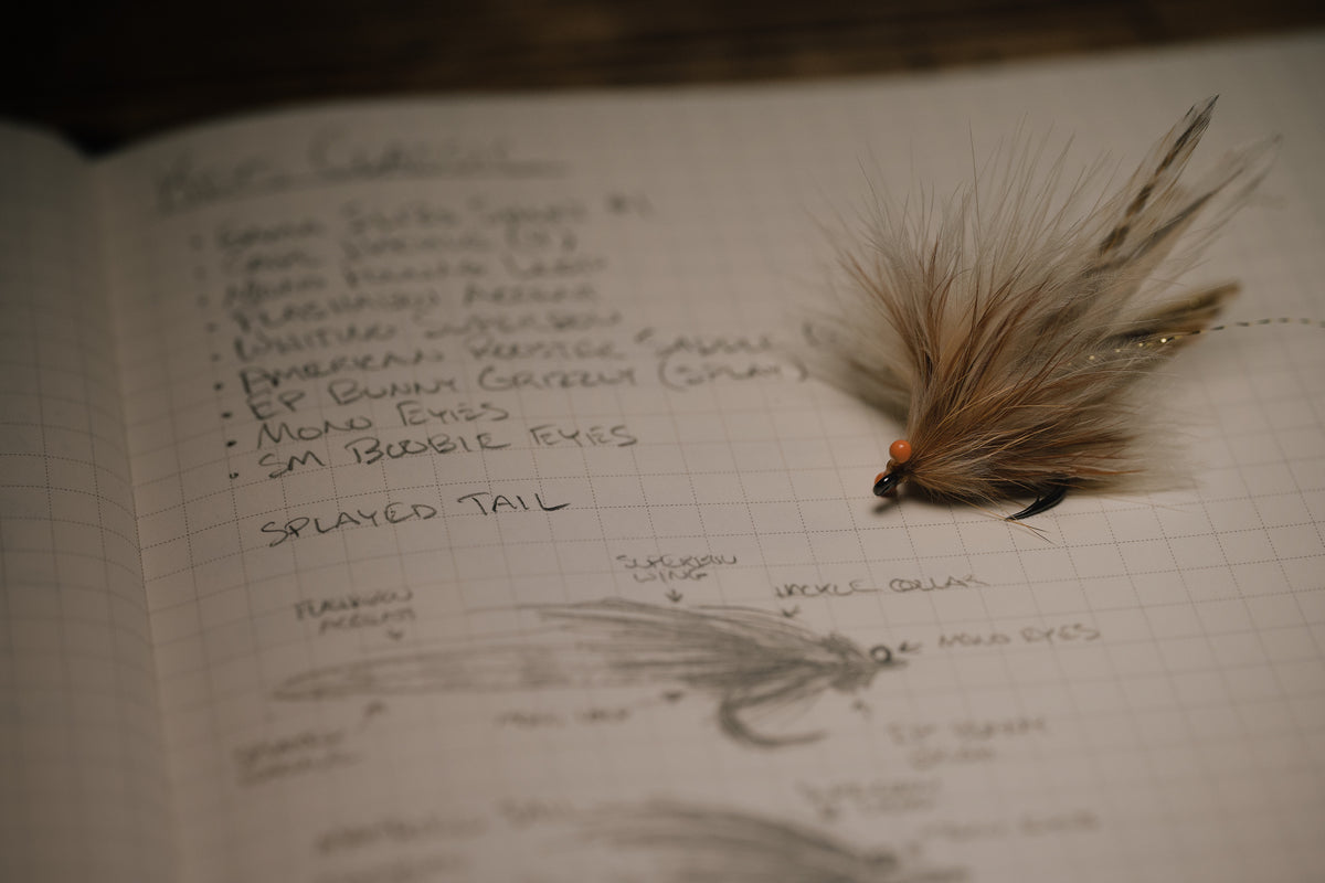 a closeup photo of the Run Around Sue tarpon fly resting on it’s page in my tying journal